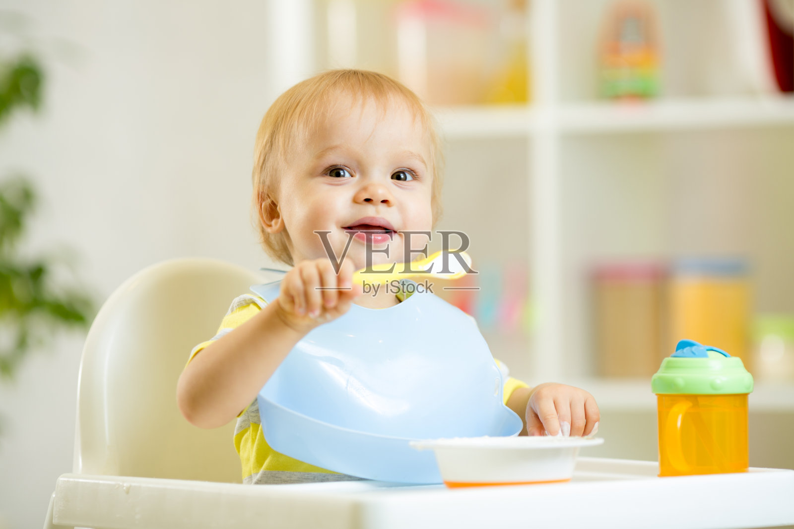 有趣的小男孩在厨房用勺子吃自己照片摄影图片
