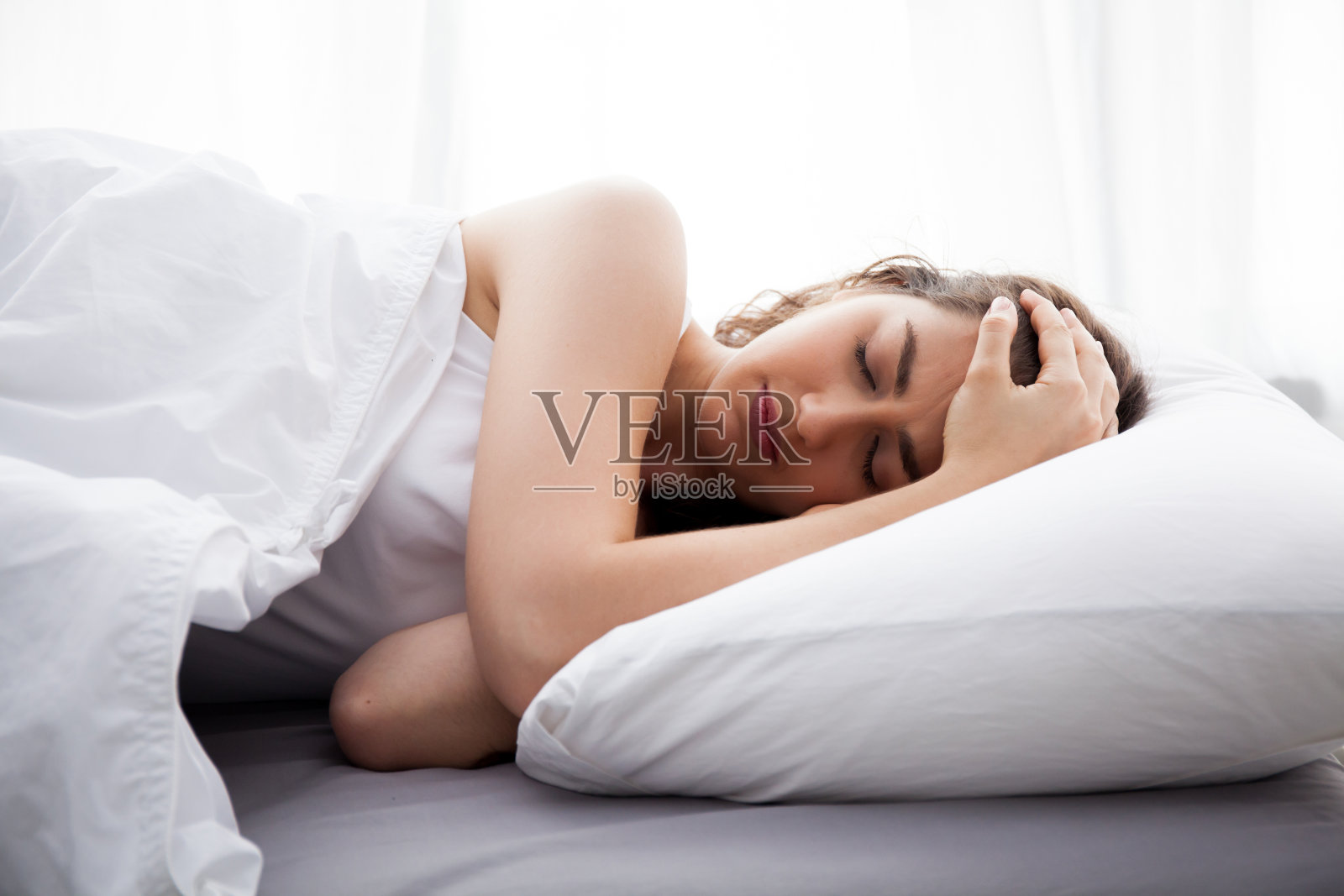 年轻漂亮的白人女人在床上头疼照片摄影图片