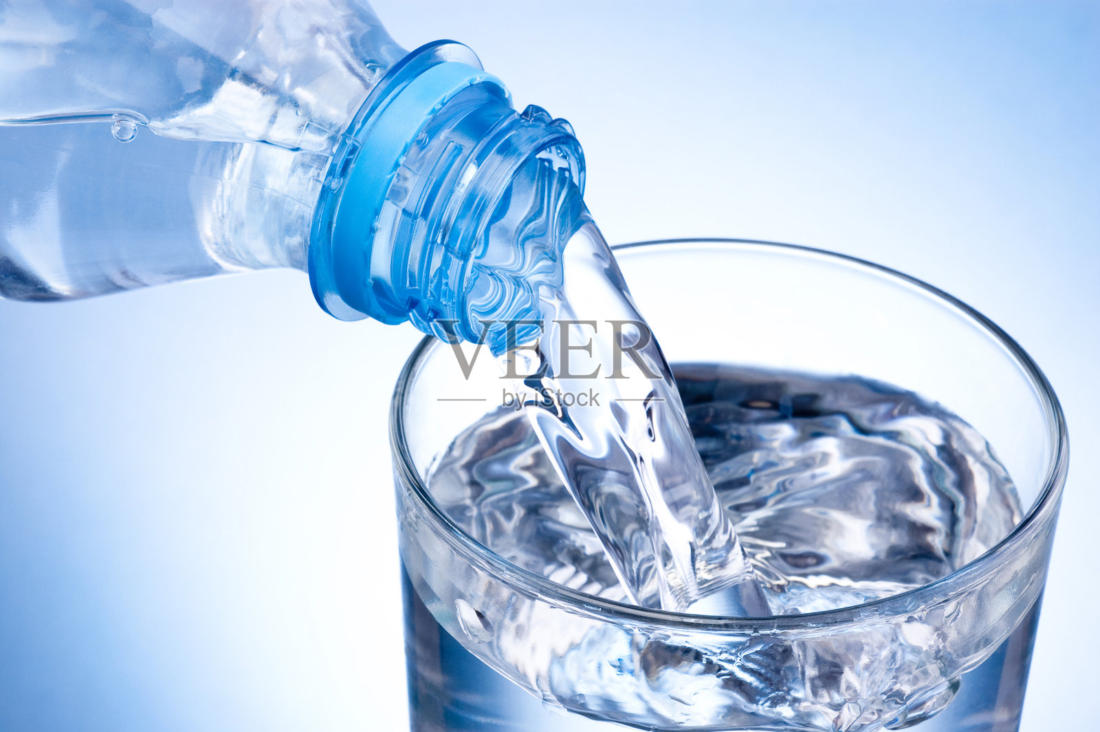 将塑料瓶中的水倒在蓝色背景上照片摄影图片