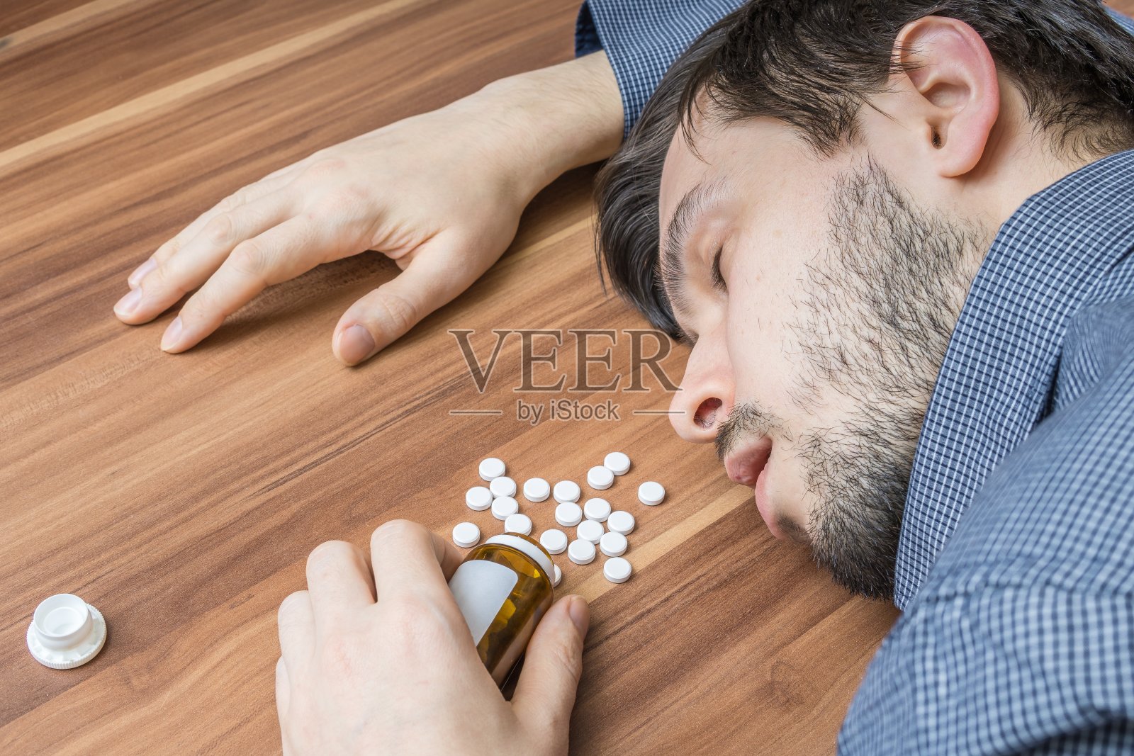 企图自杀。一个人服用了过量的药片后躺在了桌子上。照片摄影图片