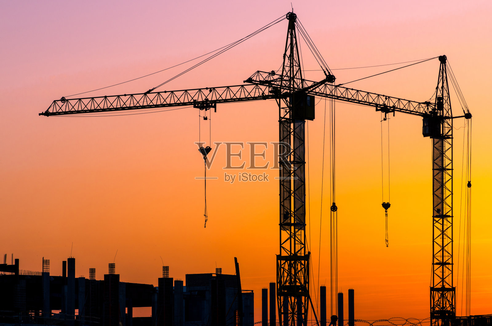 夕阳下，工业建筑起重机和建筑物的轮廓照片摄影图片