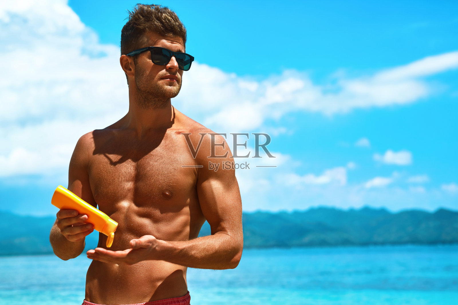 夏季护肤。男士涂抹防晒身体乳液照片摄影图片