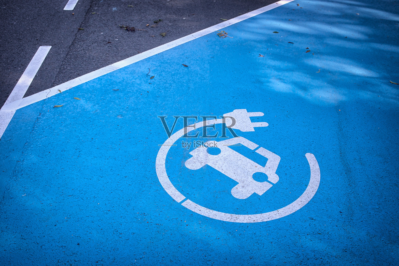 蓝色停车场上有“在此充电”的标志照片摄影图片