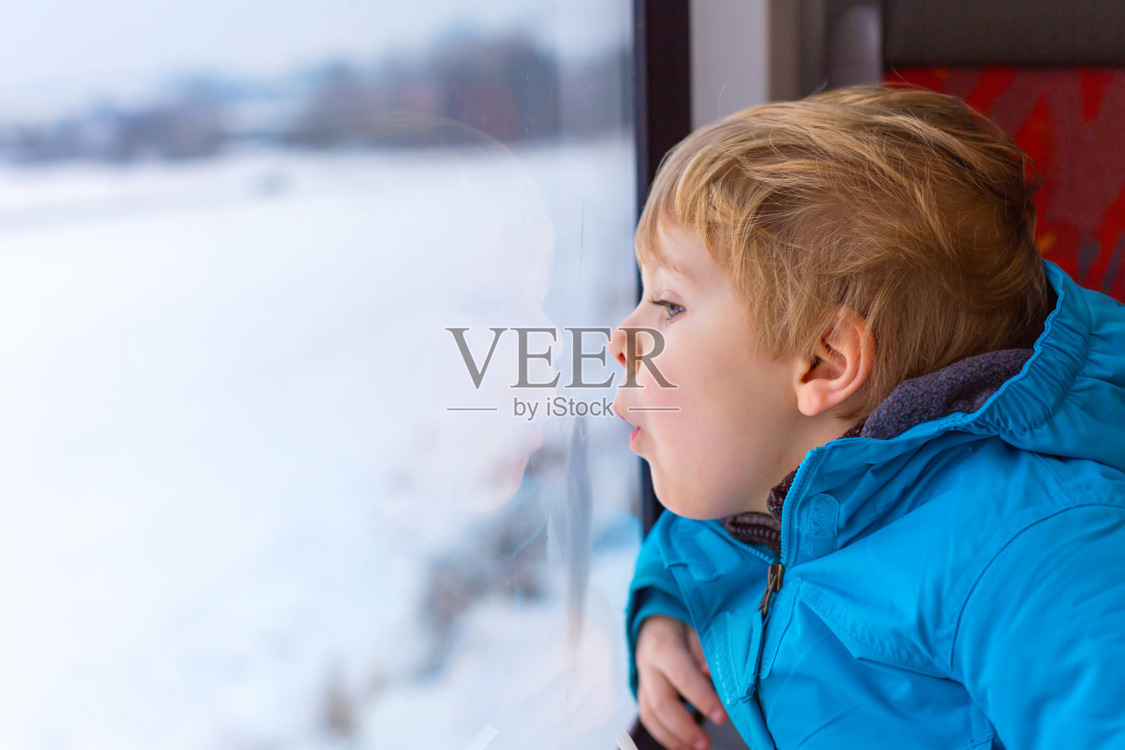 可爱的蹒跚学步的小男孩望着火车窗外照片摄影图片