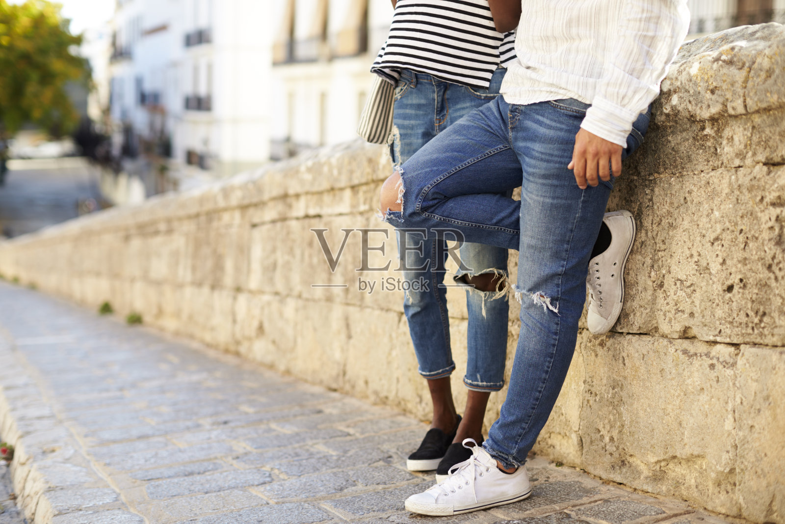 一对夫妇倚靠在西班牙伊比沙岛的一堵墙下照片摄影图片
