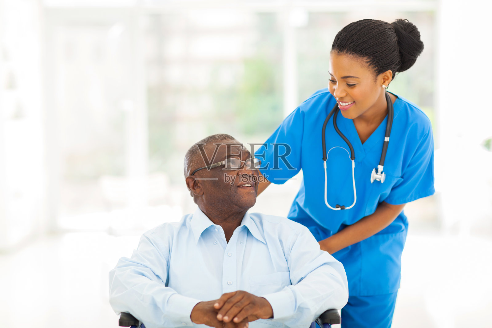 照顾坐轮椅的老年病人的非洲护士照片摄影图片
