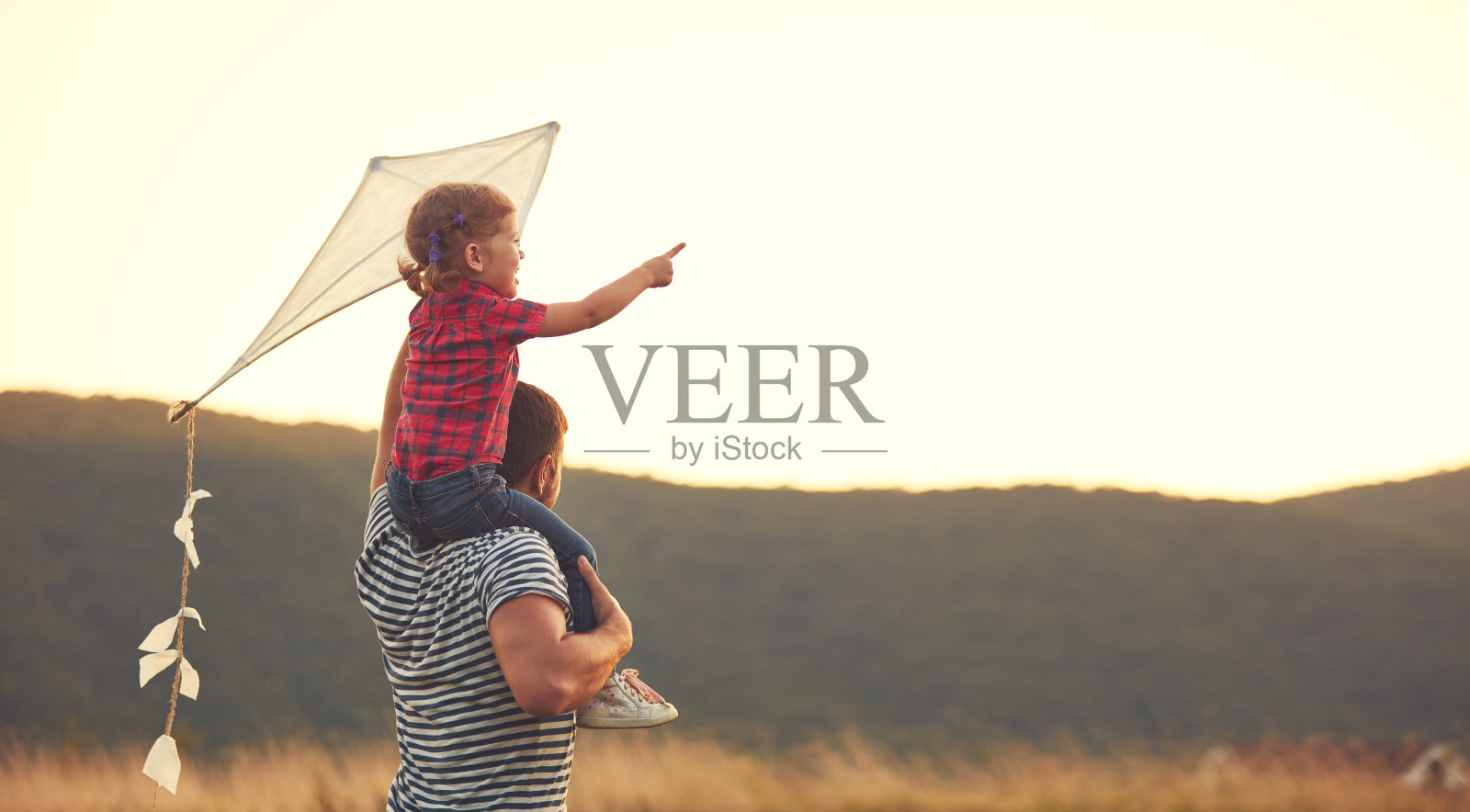 幸福的家庭，父亲和孩子在草地上放着风筝照片摄影图片