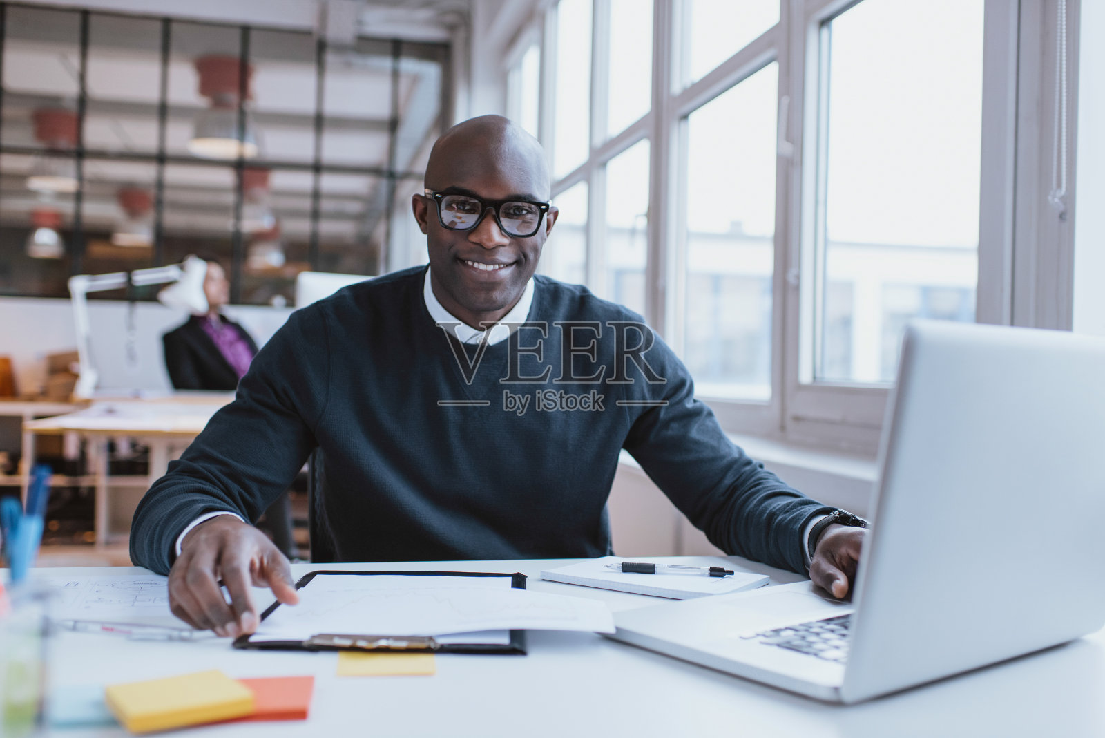 一个自信的年轻人坐在他的办公桌前照片摄影图片