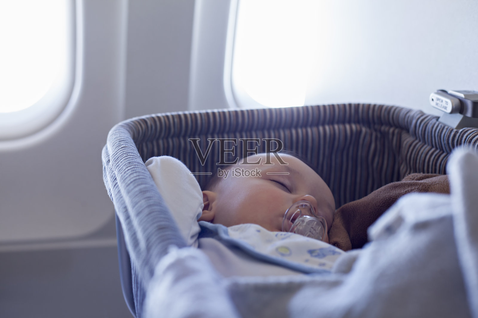 在飞机上的摇篮里睡觉的男婴照片摄影图片