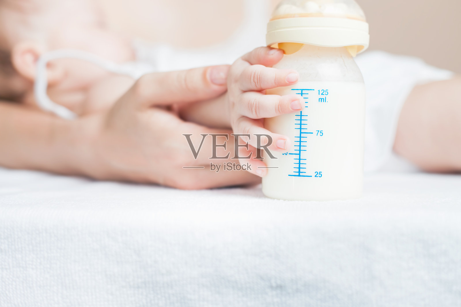 婴儿抱着装着母乳的奶瓶照片摄影图片