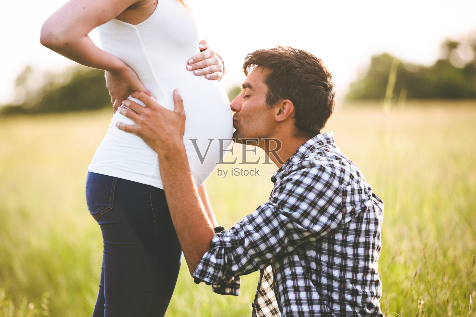 年轻男子亲吻孕妇的肚子照片摄影图片