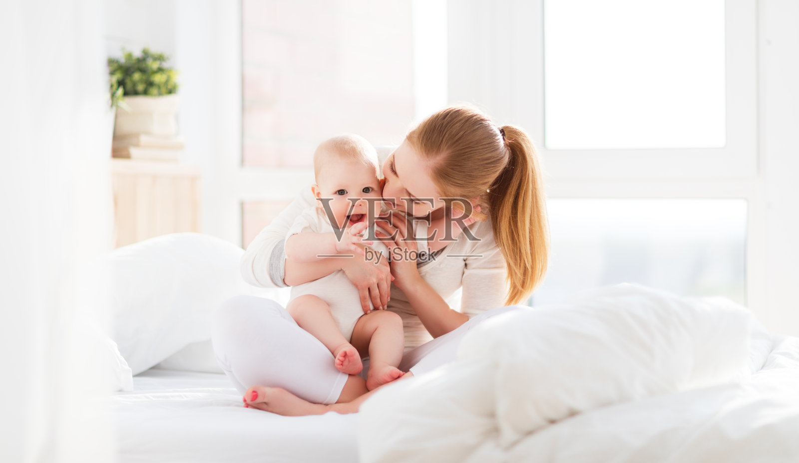 快乐的家庭妈妈和宝宝在床上玩耍和拥抱照片摄影图片