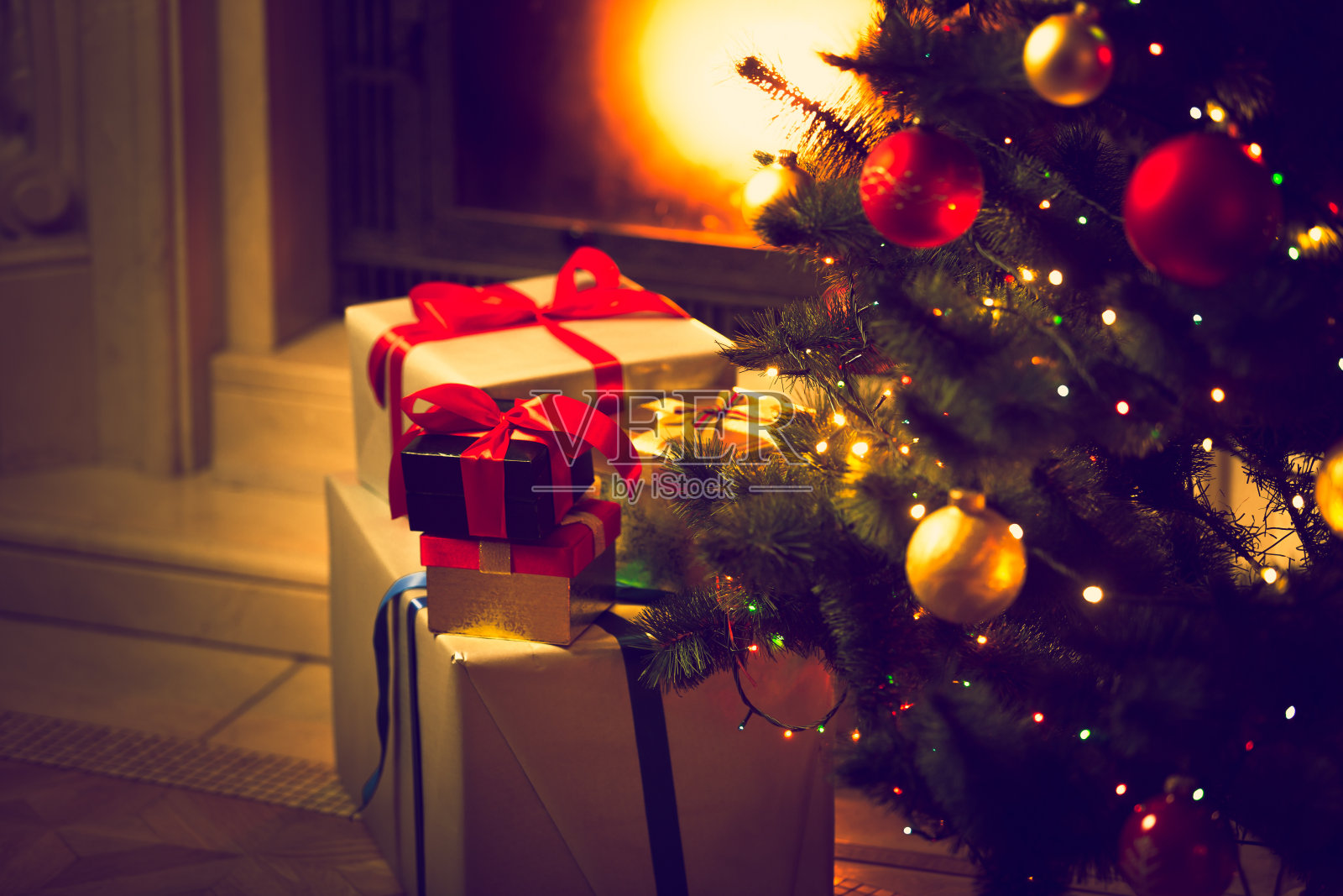 圣诞树和礼品盒对着燃烧的壁炉照片摄影图片