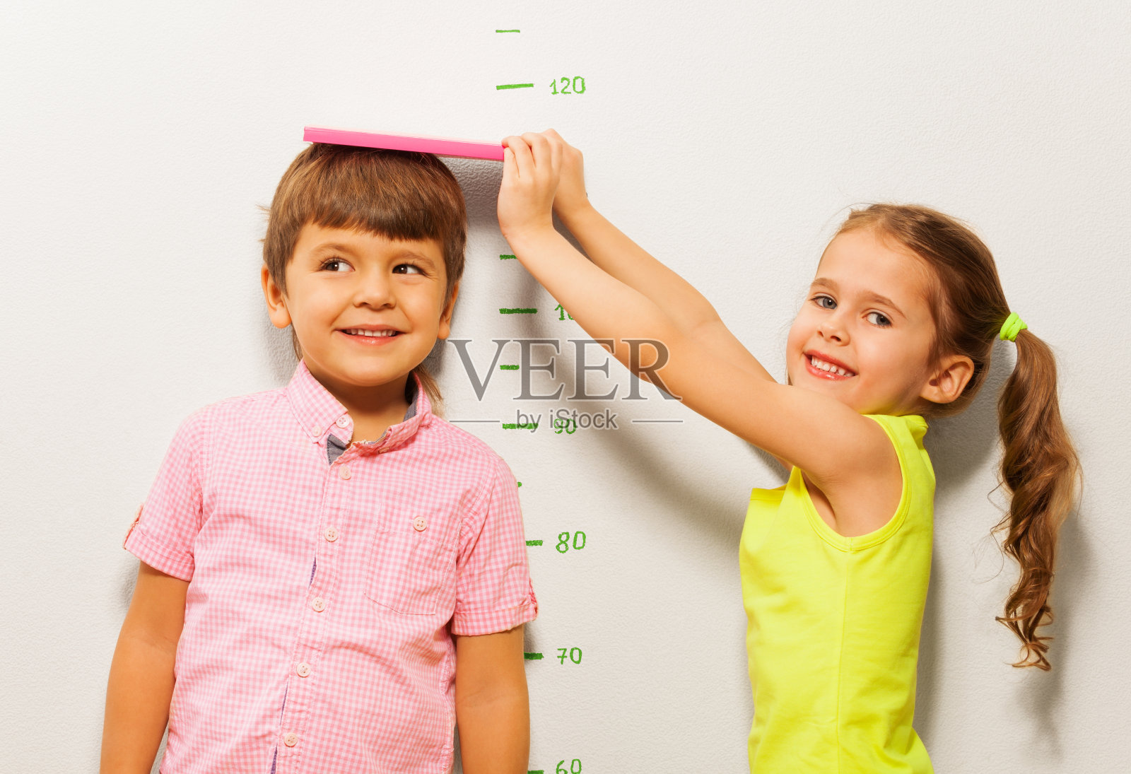 男孩和女孩在家用墙秤测量身高照片摄影图片