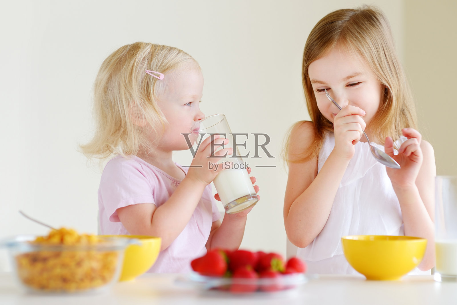 两个可爱的小妹妹在厨房里吃麦片照片摄影图片