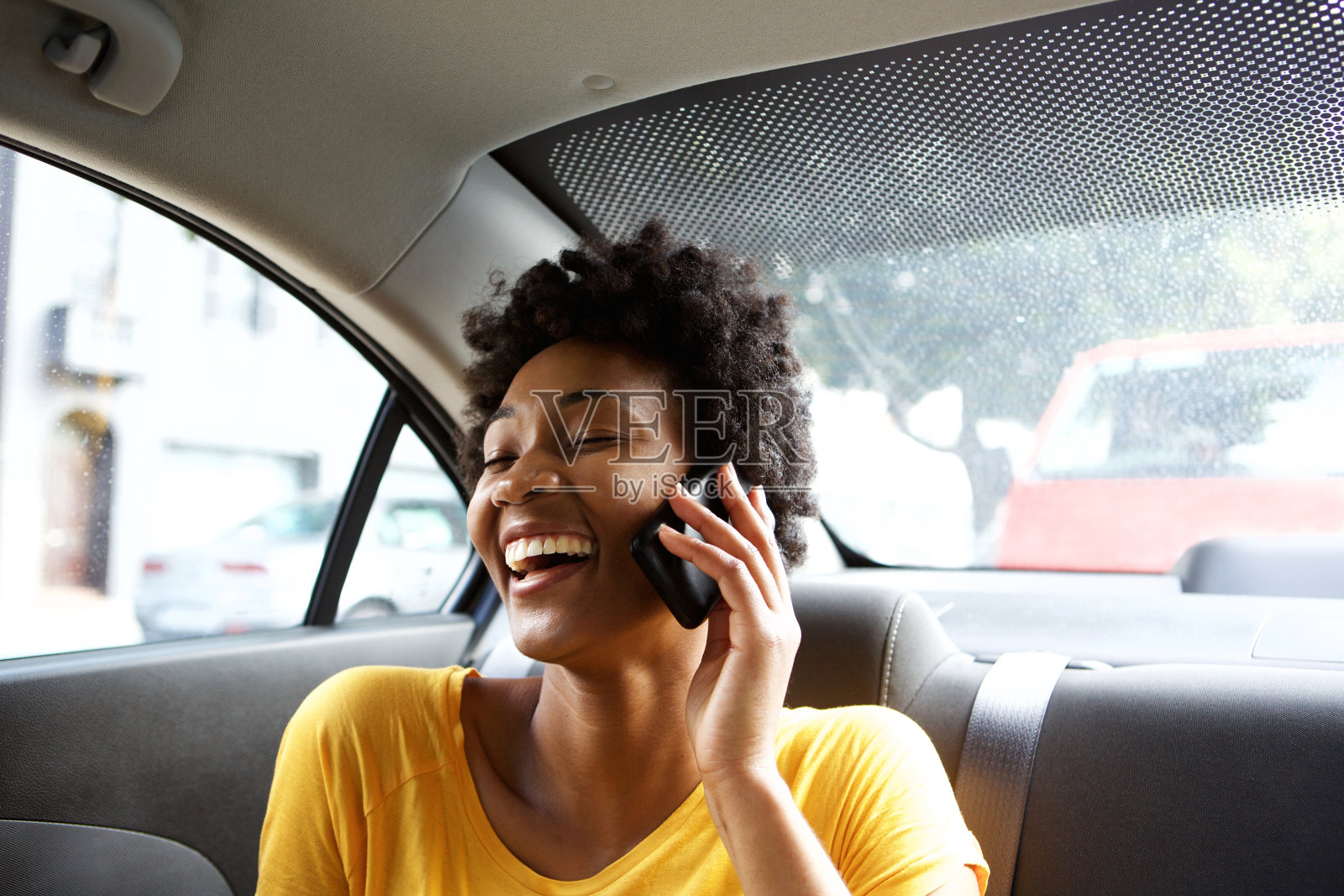 笑着的年轻女子在车里打电话照片摄影图片