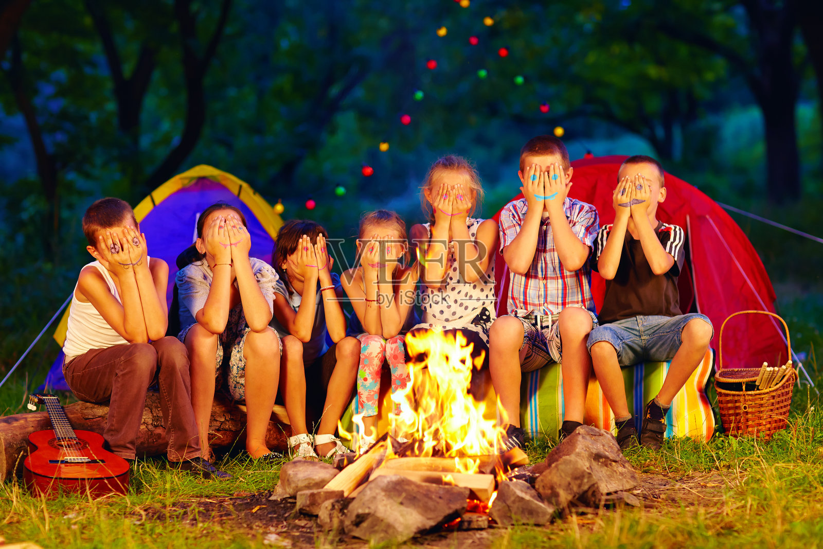 手上画着脸的孩子们围坐在篝火旁照片摄影图片