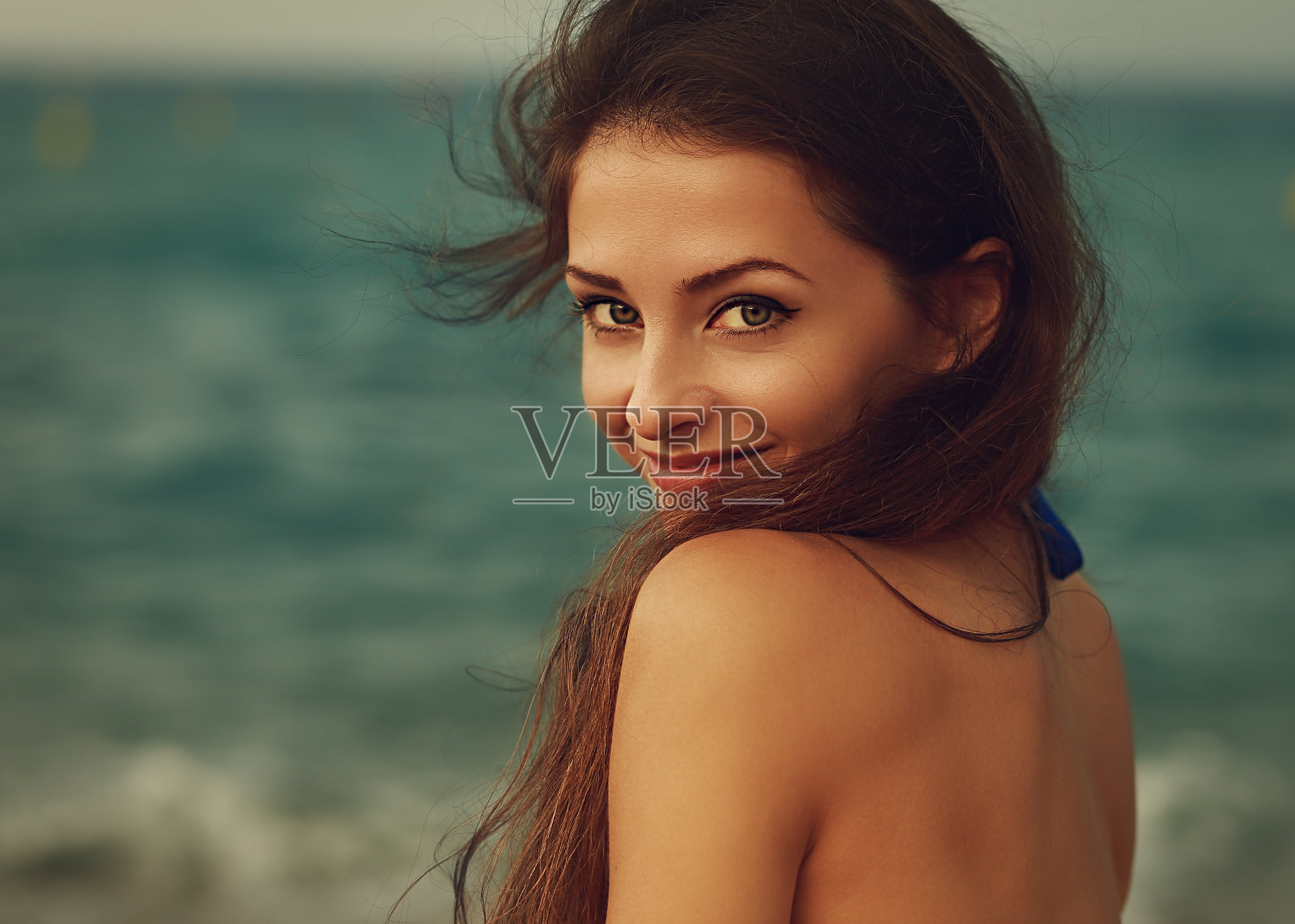 微笑的年轻女子看起来快乐的海洋背景。特写镜头照片摄影图片