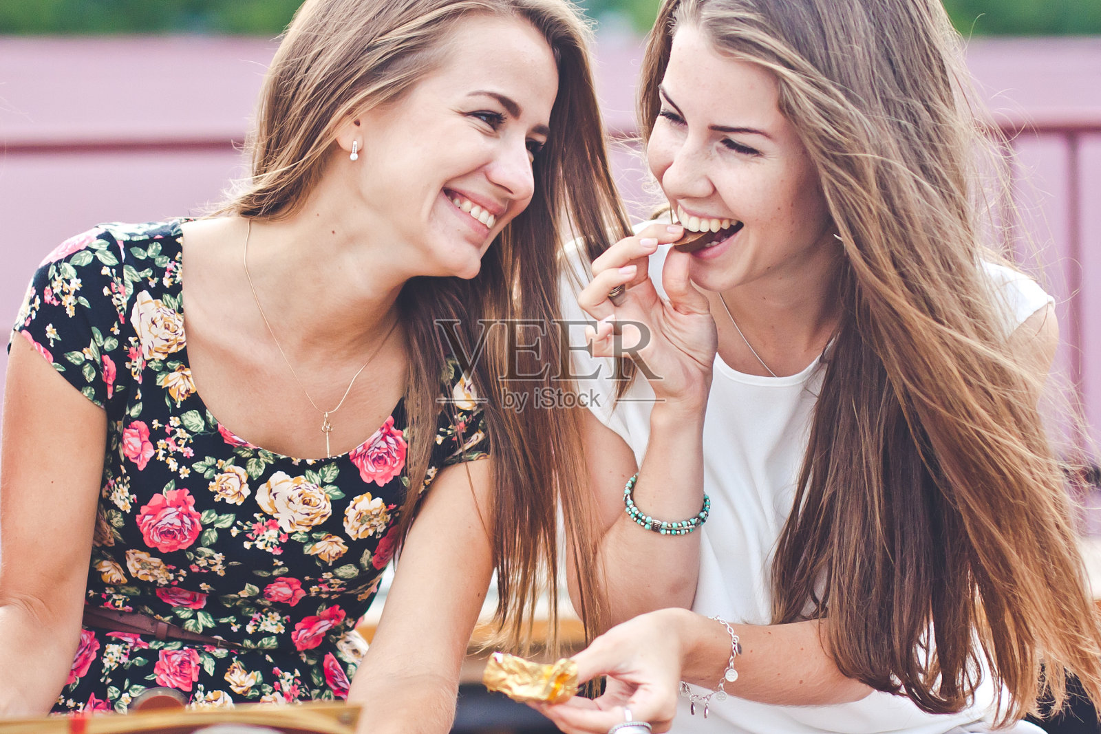 两个年轻迷人的女性在户外吃巧克力，谈笑风生照片摄影图片