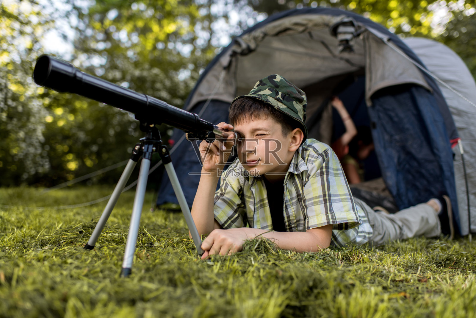 一个小探险家在露营时用望远镜看东西。照片摄影图片