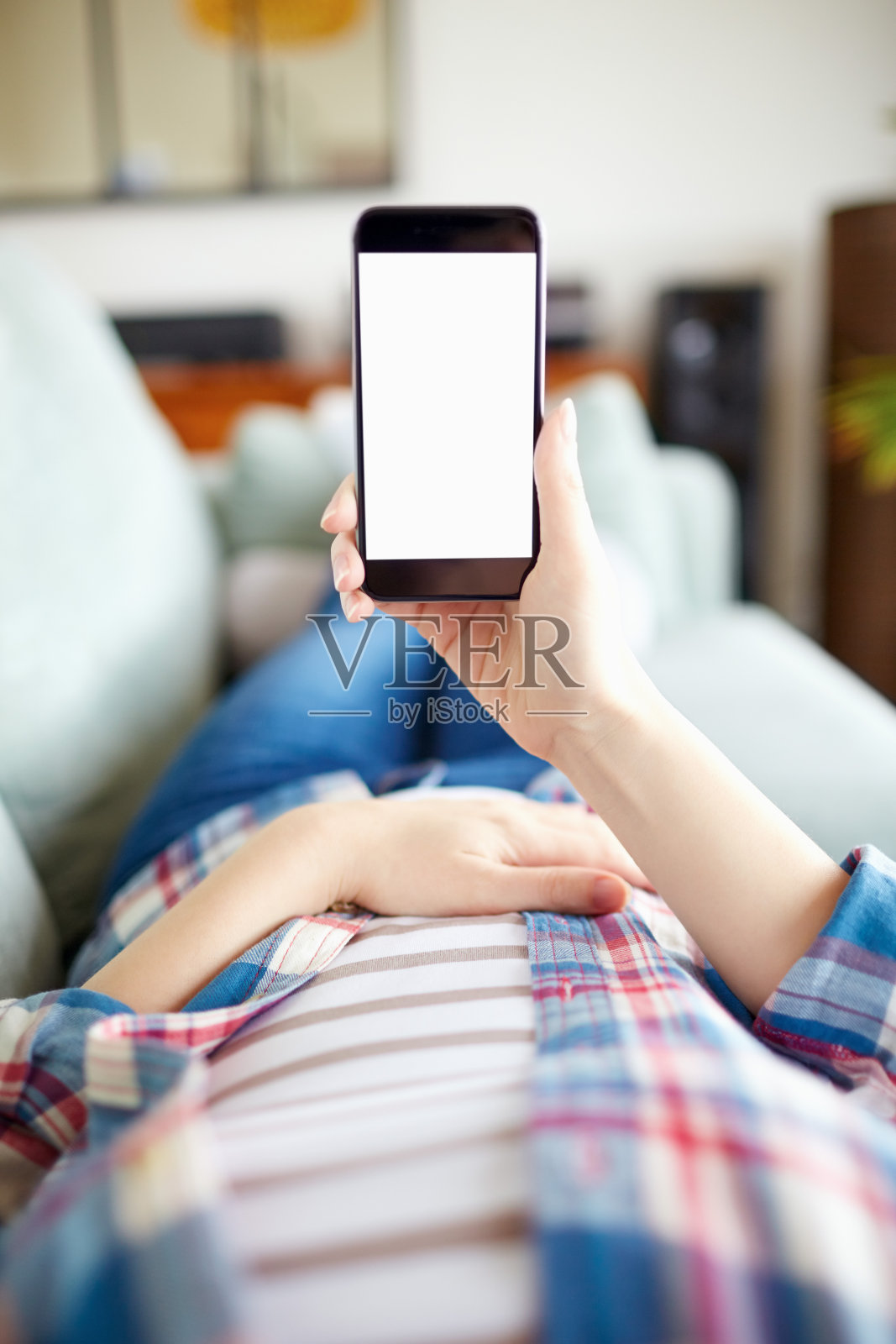 坐在沙发上拿着智能手机的轻松女人的POV照片摄影图片