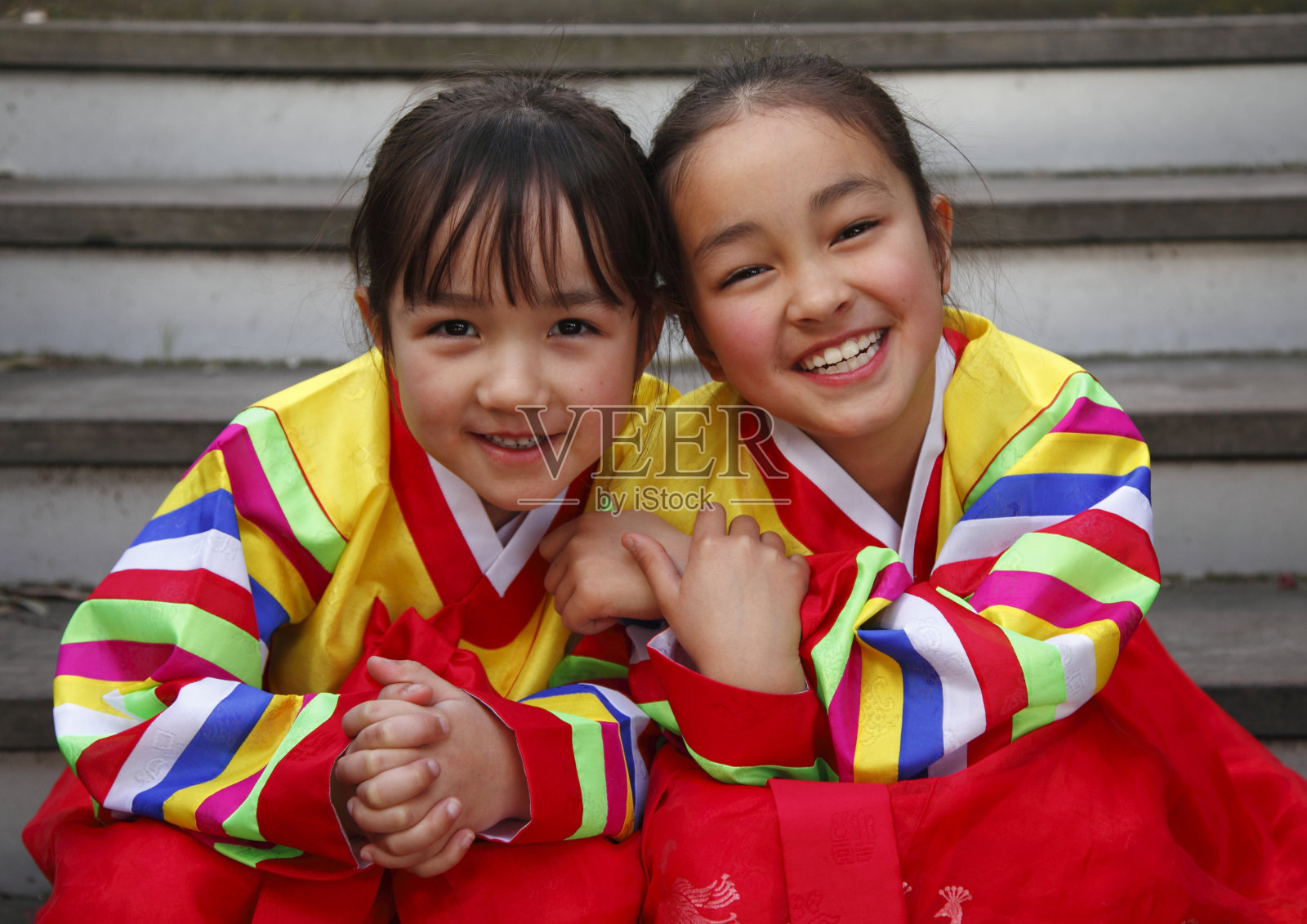 快乐的韩服——两个年轻的女孩穿着五颜六色的衣服微笑着照片摄影图片