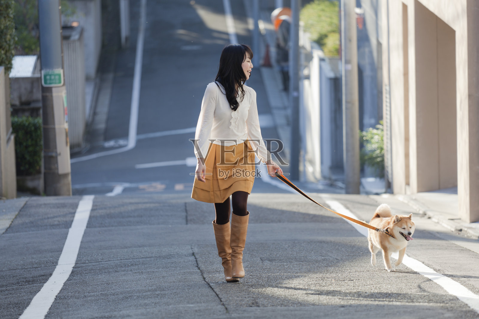 一名年轻的日本妇女在街上牵着柴犬照片摄影图片