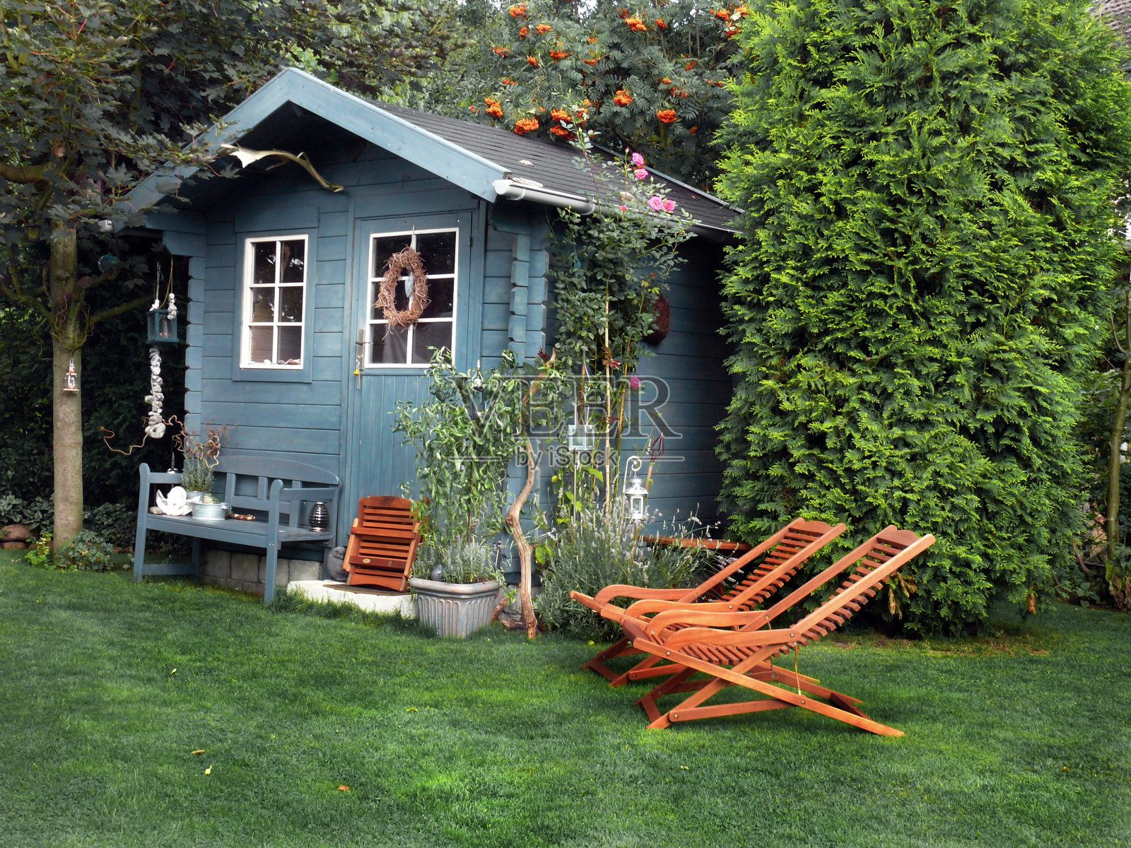 蓝色花园小屋与木制躺椅照片摄影图片