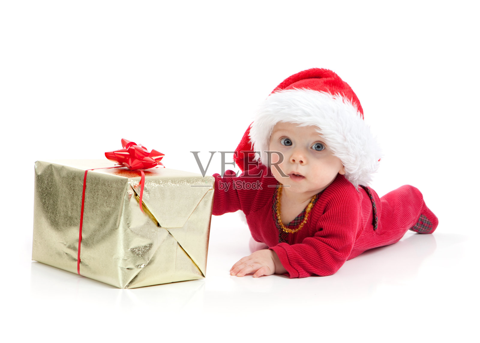 婴儿爬到圣诞礼物穿着红色的圣诞老人套装照片摄影图片