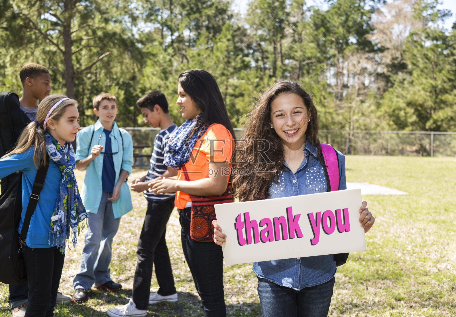 十几岁的拉丁女孩在公园里举着“谢谢”的牌子。照片摄影图片