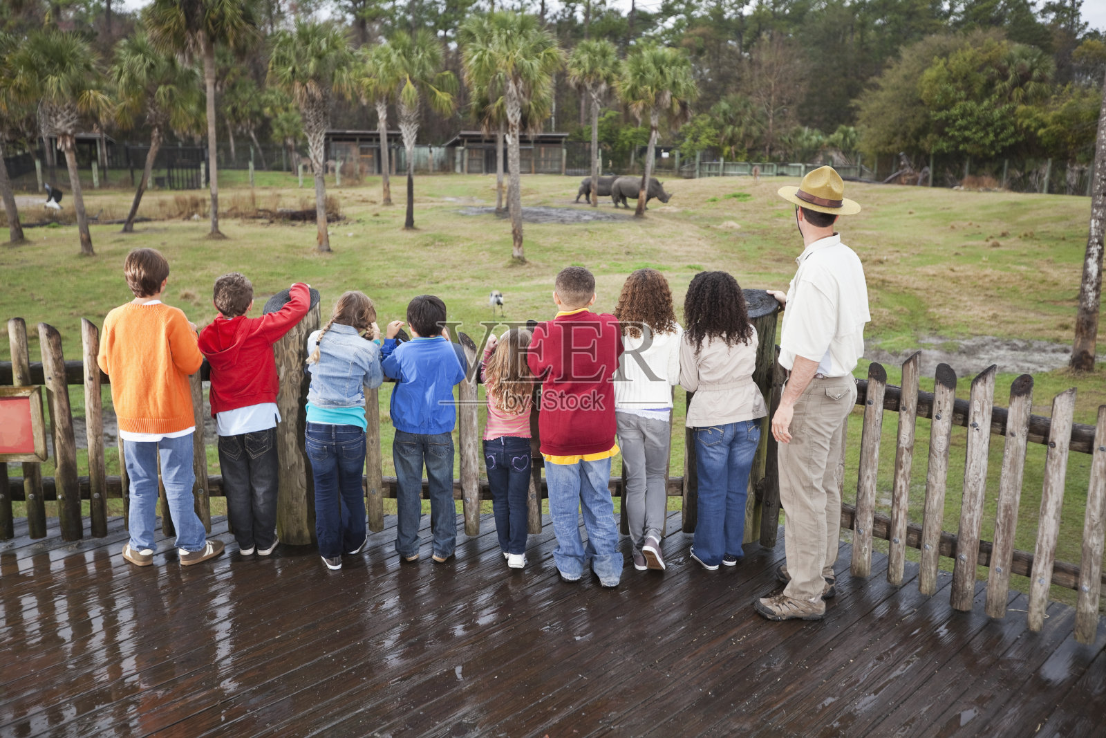 动物园管理员和一群孩子在犀牛展览照片摄影图片