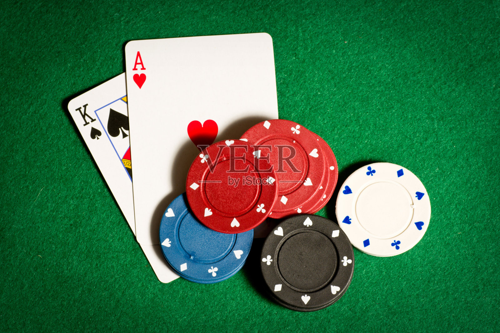 一张特写的绿色扑克桌子，上面有两张牌和空白筹码照片摄影图片