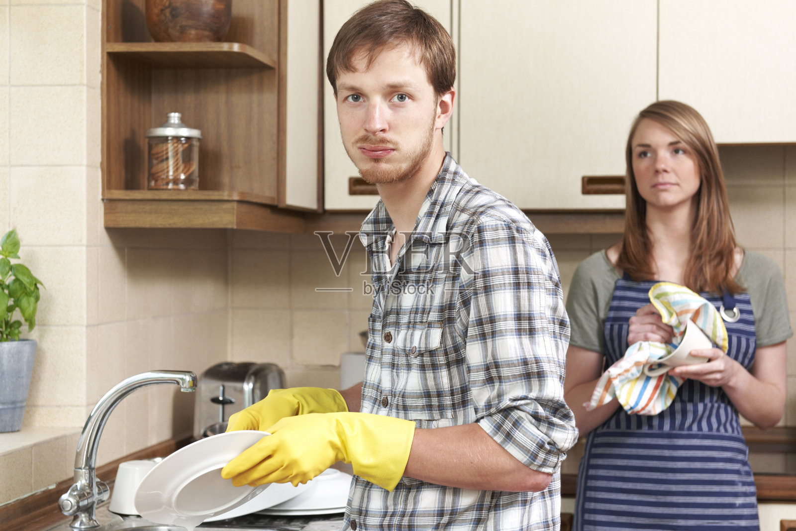 男人不情愿地和伴侣在厨房里洗碗照片摄影图片