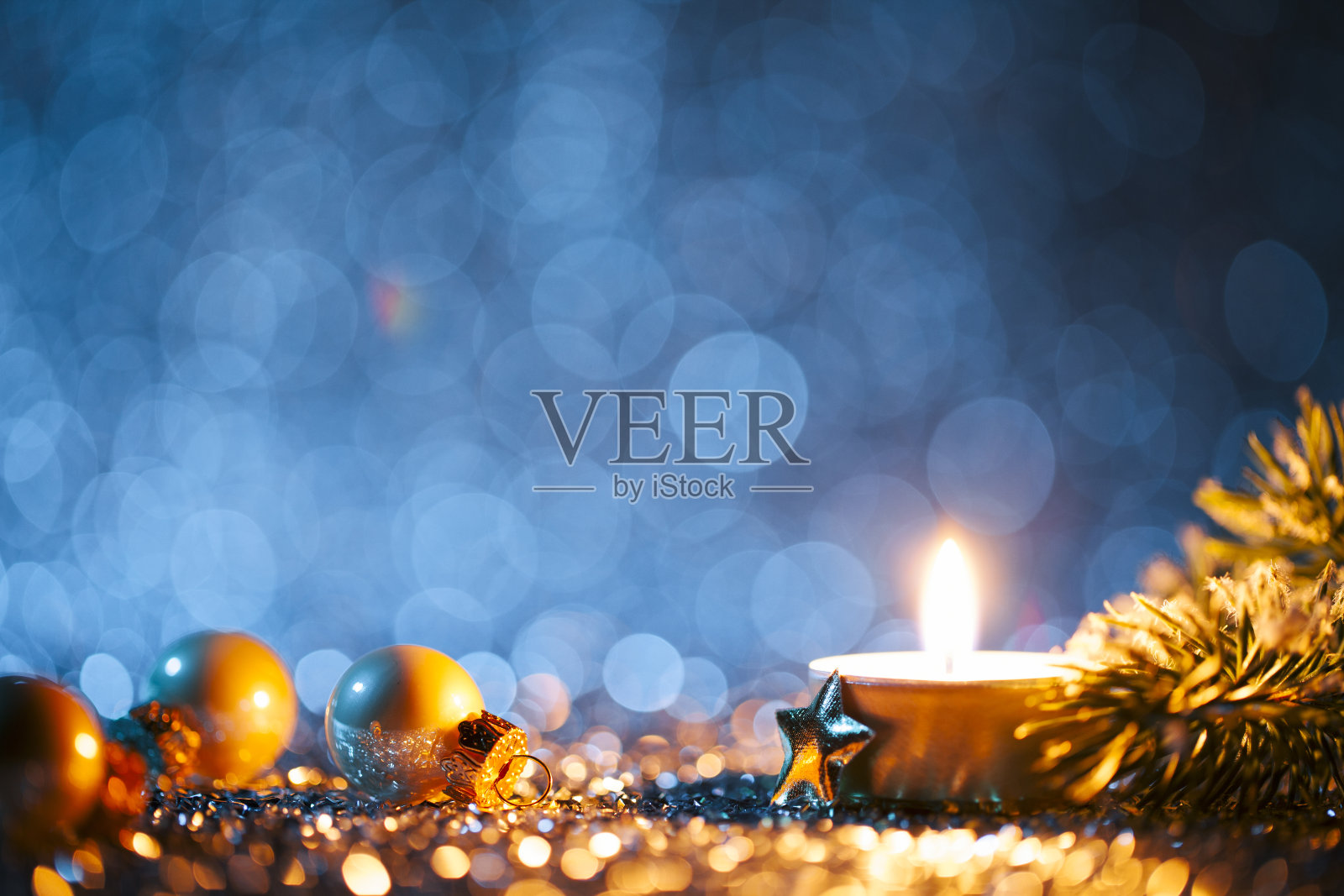 在散焦的蓝色背景上点燃的蜡烛和圣诞装饰照片摄影图片