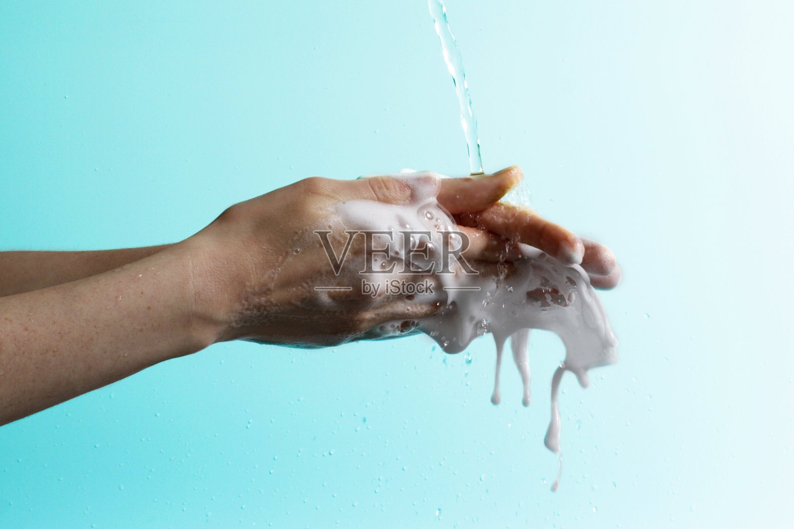 有肥皂的手和泡沫和水在梯度蓝色背景照片摄影图片