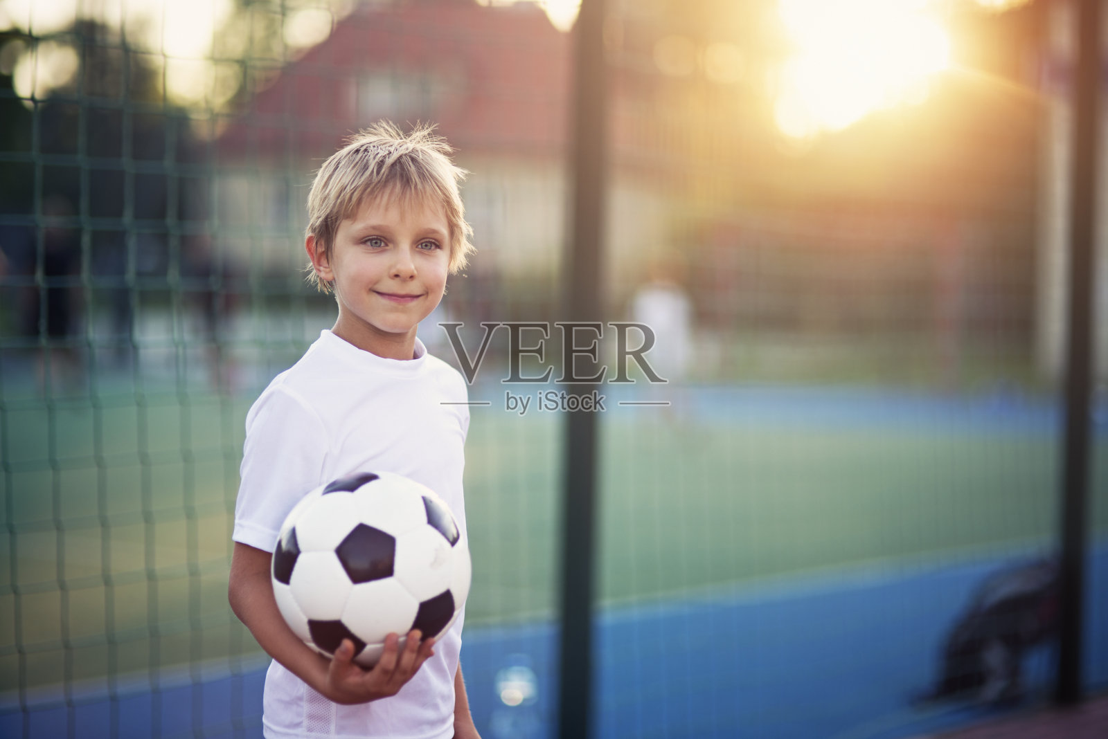 小男孩在校园里踢足球照片摄影图片