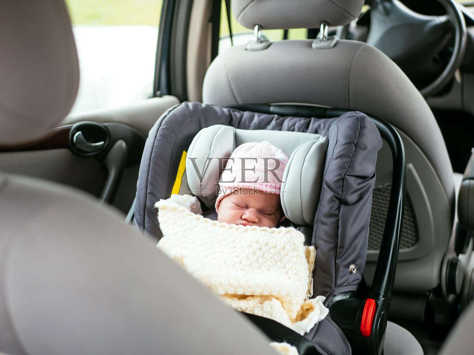 可爱的两周大的婴儿睡在汽车后座的汽车座椅上照片摄影图片