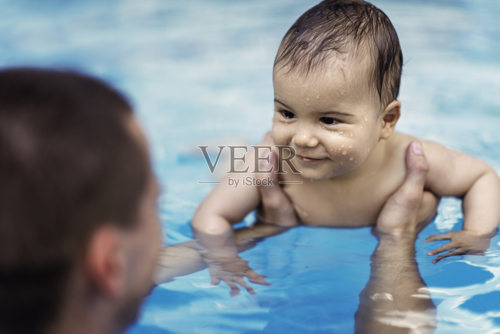 在游泳池里微笑的男婴照片摄影图片