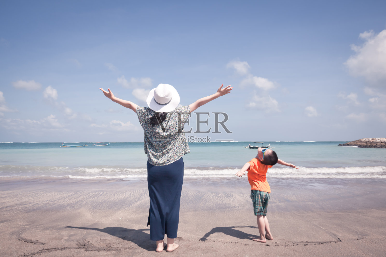 母亲和儿子在海滩上张开双臂照片摄影图片