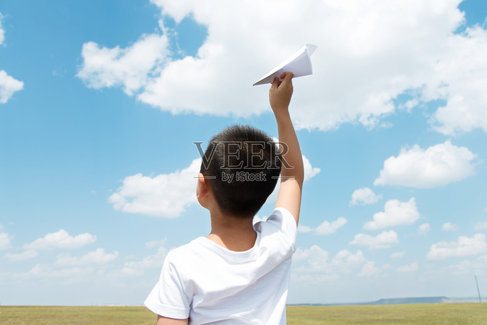 小男孩在田野里玩纸飞机照片摄影图片