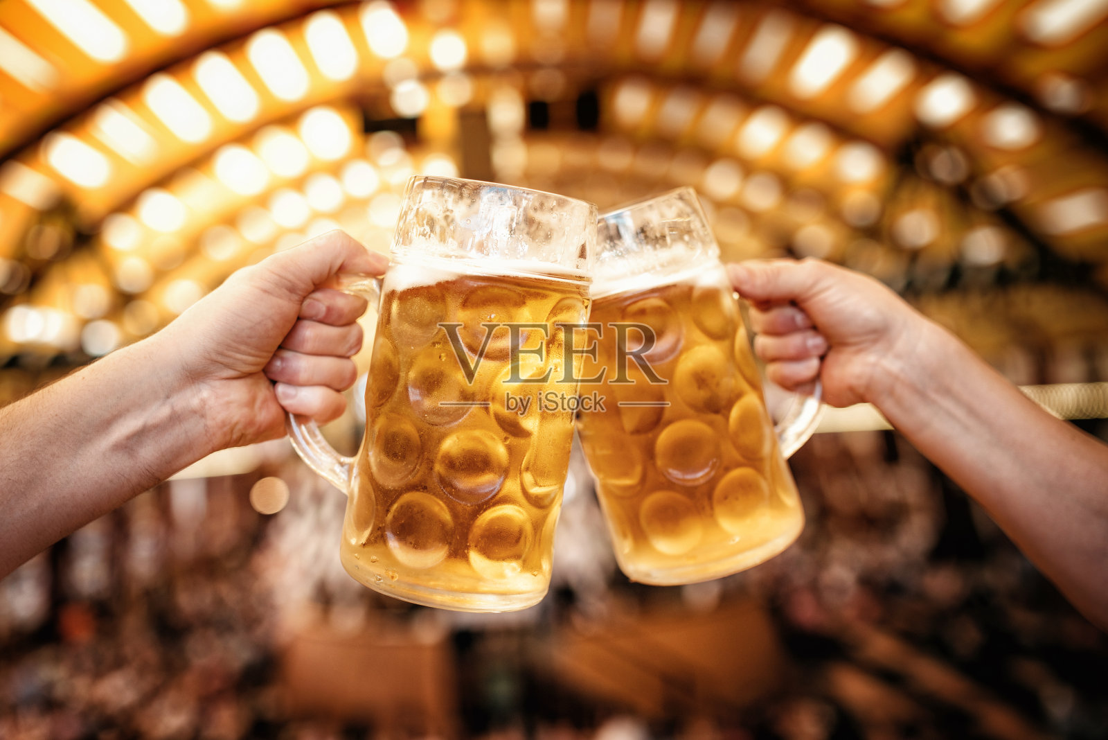 在慕尼黑啤酒节上，两只手碰杯照片摄影图片