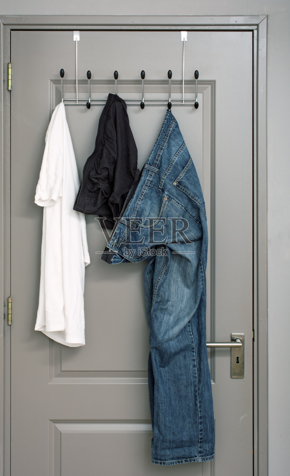 牛仔裤、t恤和短裤放在门里的衣架上照片摄影图片