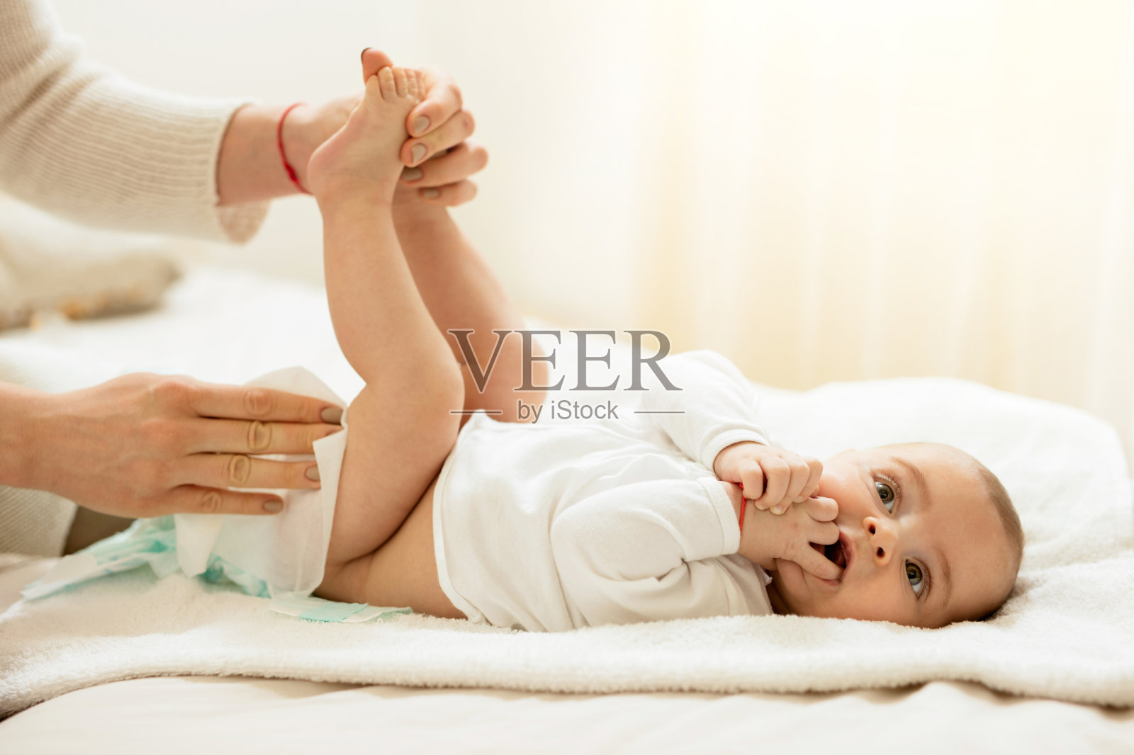 可爱的婴儿在卧室换尿布。照片摄影图片
