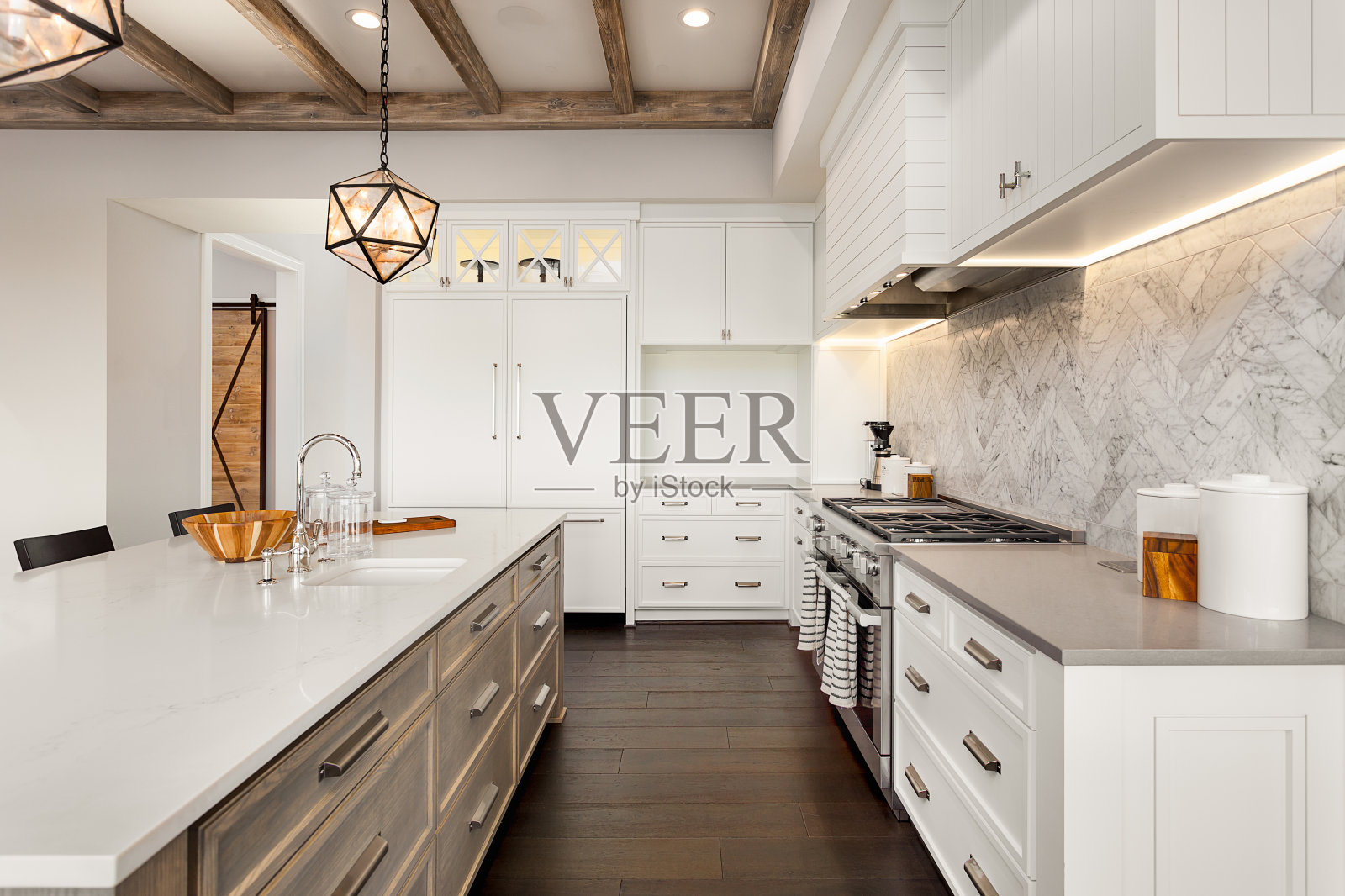 美丽的厨房在新的豪华家庭岛，吊灯，和硬木地板。照片摄影图片