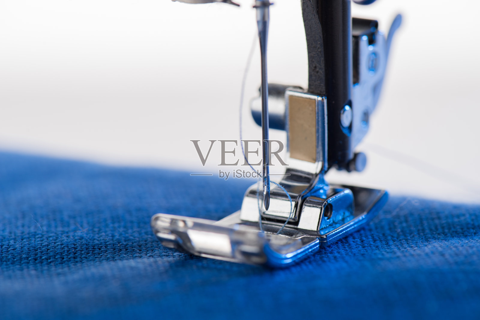 缝纫机缝纫蓝色织物的特写视图照片摄影图片