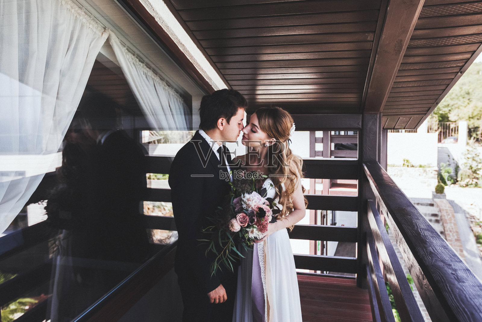 新郎在别墅阳台亲吻新娘。年轻的时尚情侣照片摄影图片