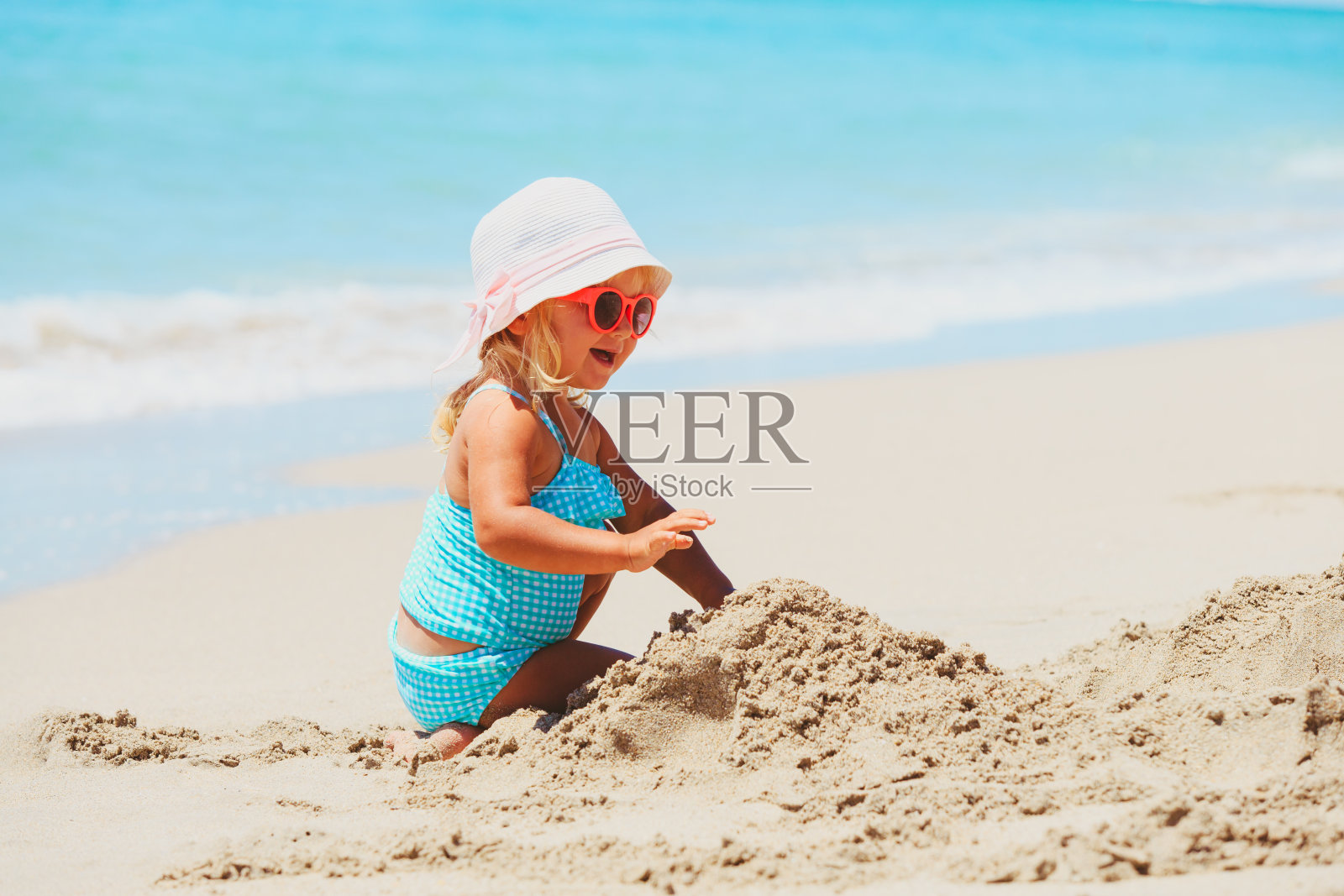 可爱的小女孩在沙滩上玩沙子照片摄影图片