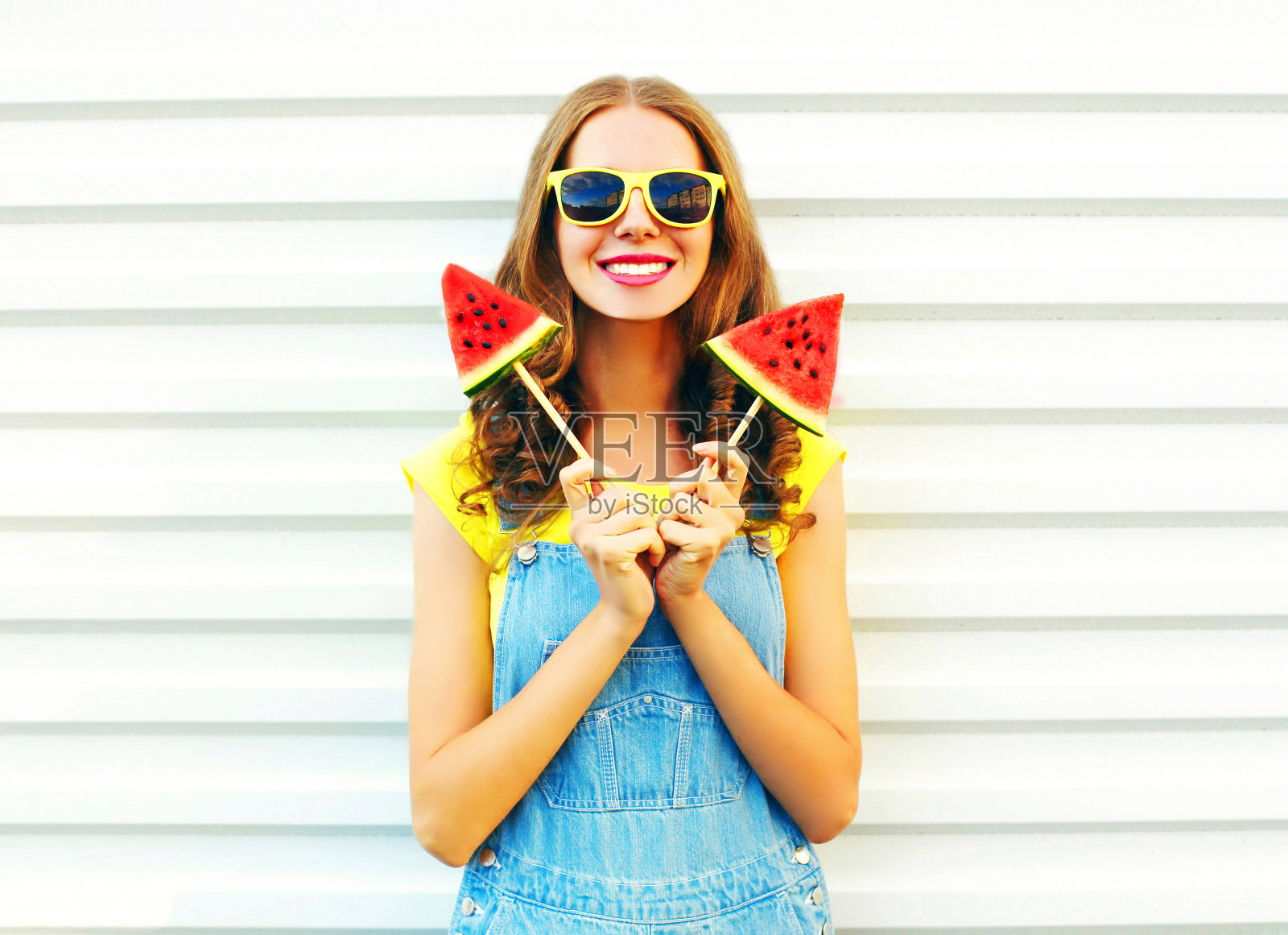 在白色的背景上画一个快乐微笑的女人，她拿着两片西瓜做成的冰淇淋照片摄影图片