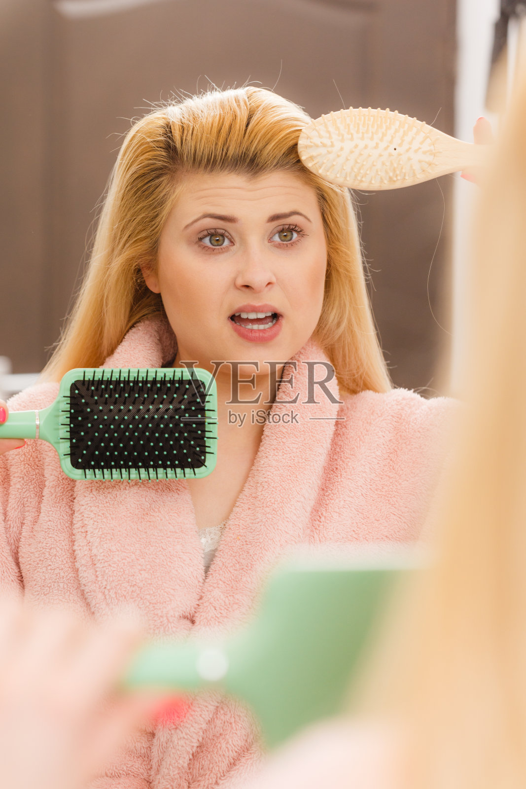 震惊的女人穿着晨衣梳理她的头发照片摄影图片