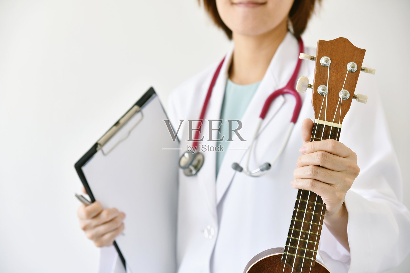 医生手握尤克里里(乐器)，音乐疗法的概念。照片摄影图片